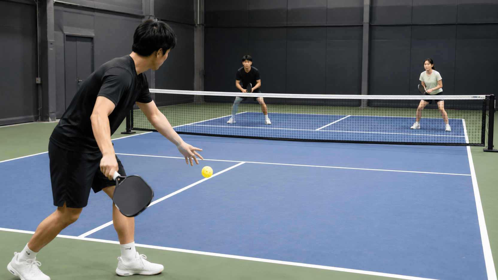 屋内コートでピックルボールのサーブを行う日本人プレイヤー